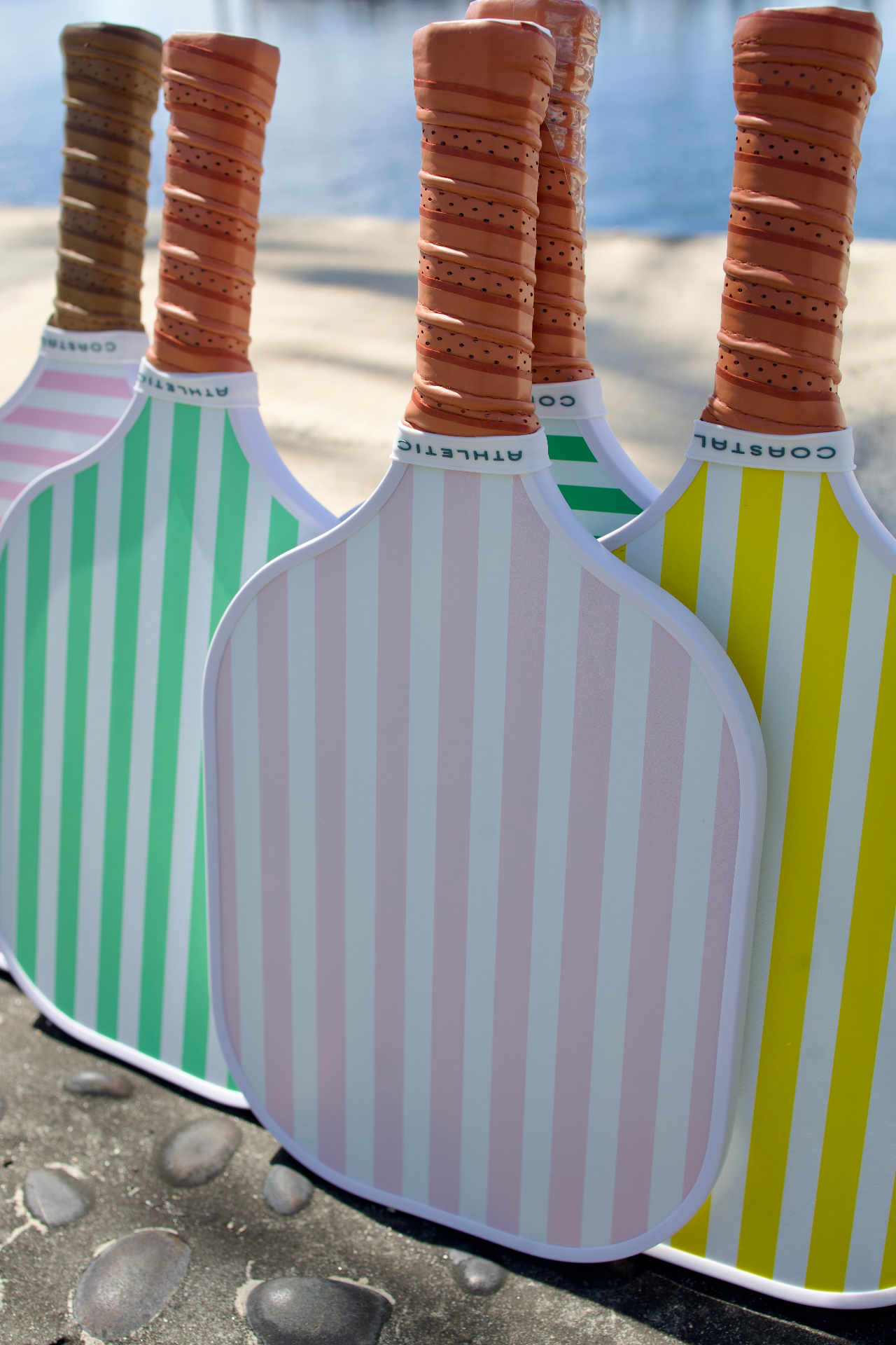 Close-up of striped Coastal Athletic paddles by the water