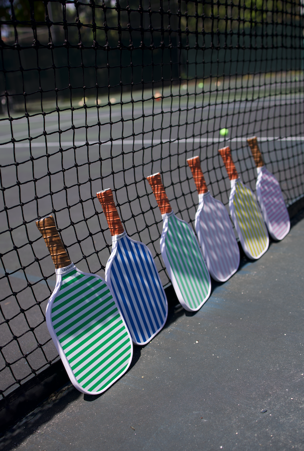 Striped Coastal Athletic paddles leaning against the court net