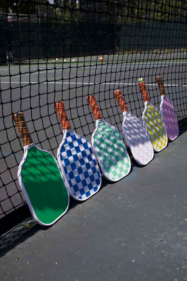 Checkered Coastal Athletic paddles leaning against the court net
